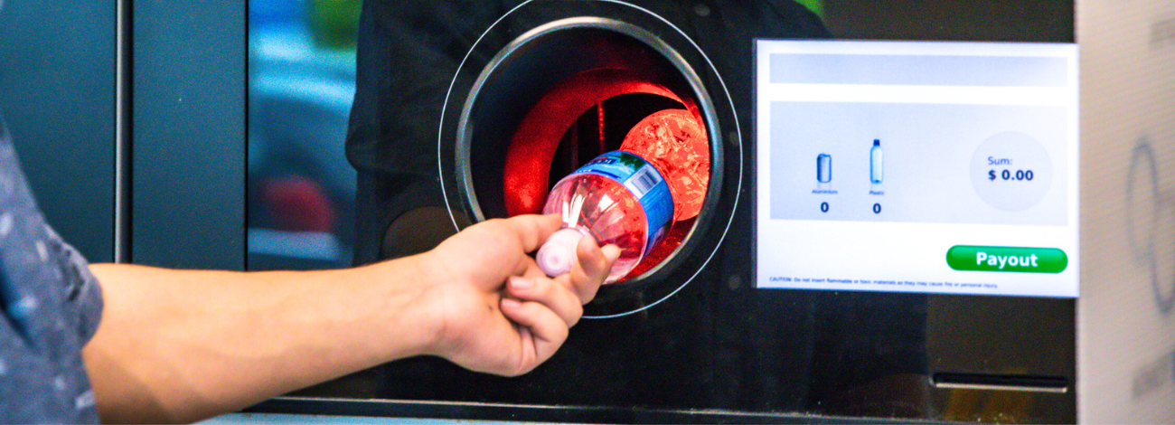 A man pushes a plastic bottle into a bottle return machine