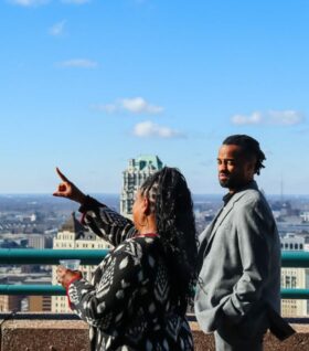 Alisha Bell points off into the Detroit skyline at a 2024 soiree