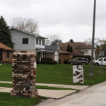 A row of bungalow houses reveal a blighted Saginaw home across the street