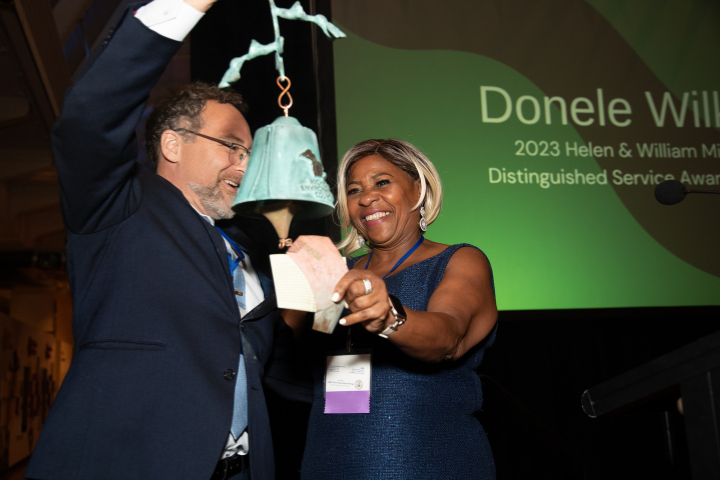 Donele Wilkins rings a bell held by Conan Smith at the 2023 annual event in Dearborn.