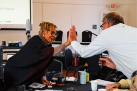 Deborah Stewart Anderson and Eric Schertzing high five each other during the 2023 member meeting in Detroit.