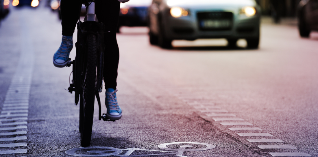 A bicyclist follows a bike lane down a busy street