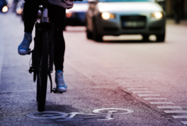 A bicyclist follows a bike lane down a busy street