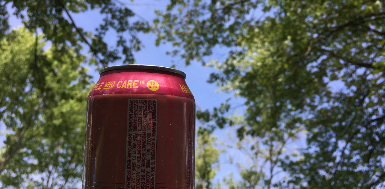 A pink beer bottle is held up to the sky