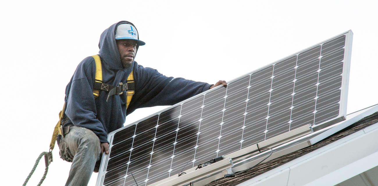 A worker installs a solar panel on the Michigan Environmental Council's Lansing office