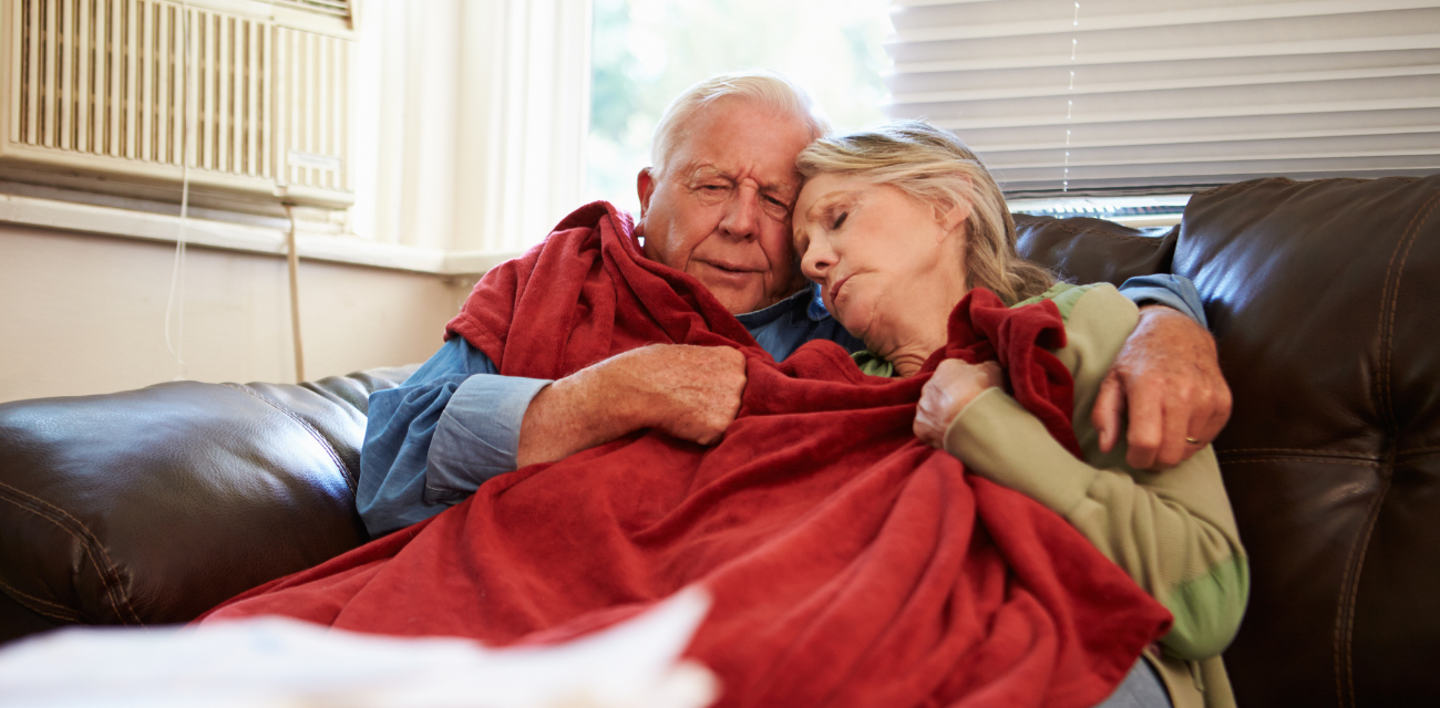 An older couple tries to keep warm with a blanket