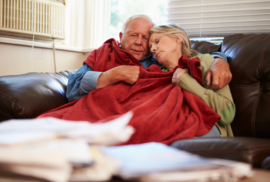 An older couple tries to keep warm with a blanket