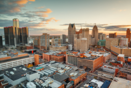 Buildings of Detroit's skyline are cast ochre colors in the setting sun