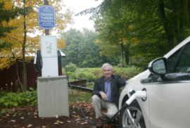 Someone poses with an electric vehicle in 2011