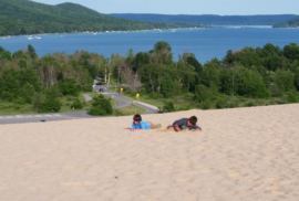 Two kids lie atop a sand dune in Michigan