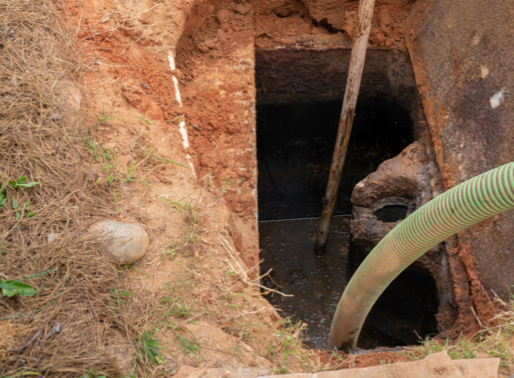 A man holds a tube as he cleans a septic tank