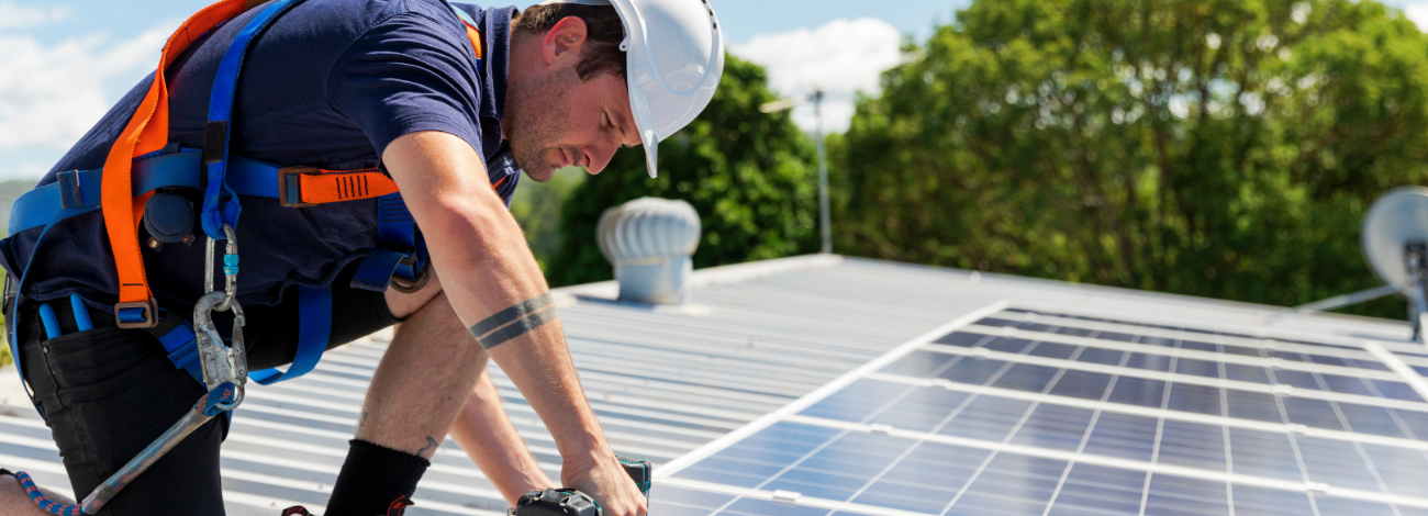 A man installs solar rooftop solar panels on a sunny day