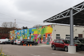 A solar car port and colorful mural make up the back side of the Allen Neighborhood Center in Lansing