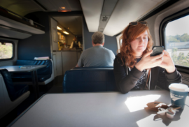 An Amtrak train passenger checks her phone at a table en route to her destination (Courtesy of Gary Howe)