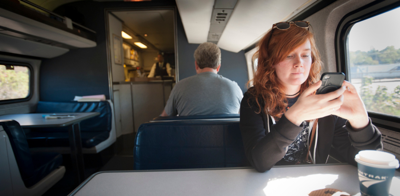 An Amtrak train passenger checks her phone at a table en route to her destination (Courtesy of Gary Howe)