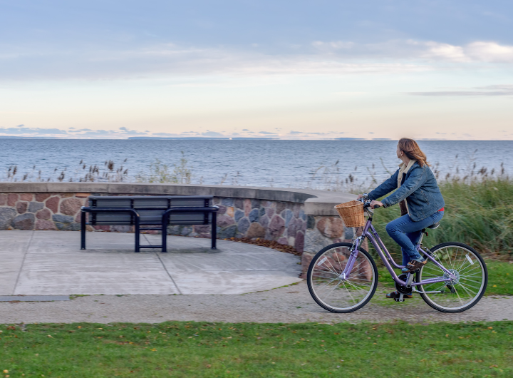 Cheerful Woman Riding Bike along Lake Superior Shoreline in Fall