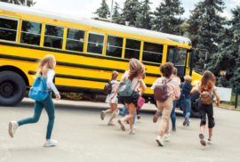 Schoolchildren run to the open door of a school bus