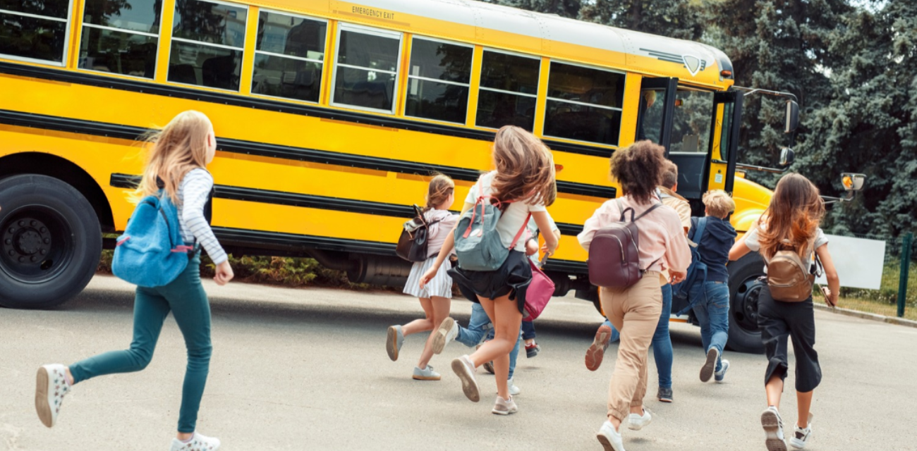 Schoolchildren run to the open door of a school bus