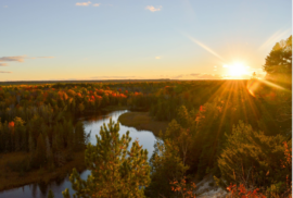 The Au Sable River shines blue amidst the ochre colors of autumn