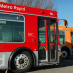 A red bus sits parked next to an orange bus