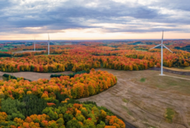 Windmills turn along an autumnal countryside in mid-Michigan