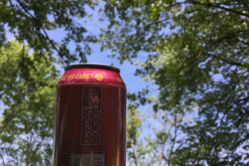 A pink beer bottle is held up to the sky