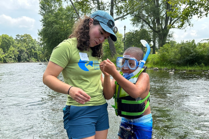 A volunteer with the Huron River Watershed Council examines something a young boy found in a local river