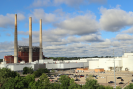 Lansing's defunct coal plant towers over a vehicle plant and trees in the heart of the city.