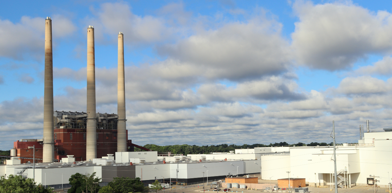 Lansing's defunct coal plant towers over a vehicle plant and trees in the heart of the city