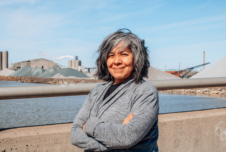 Raquel Garcia, of Southwest Detroit Environmental Vision, smiles in front of industry in Detroit (Photo by Grace Noyola.)