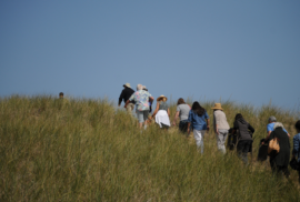 People walk up on a dune crest at Saugatuck's Oval Beach (Photo by Nate Mathewson)