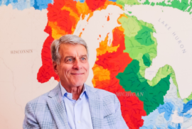 A photo of John Erb, chairman for the Erb Family foundation, seated in front of a large map of Michigan's watersheds.