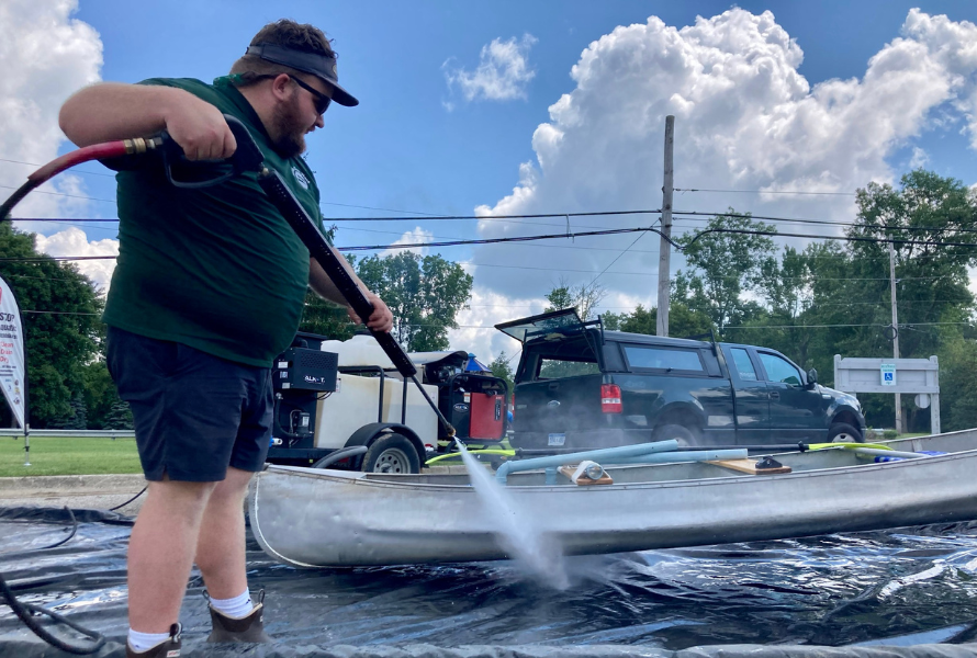 A person washes a canoe to stop the spread of invasive species. (Photo courtesy of Michigan Lakes & Streams Association)