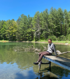 Cody Gallagher relaxing on a dock on a forested lake