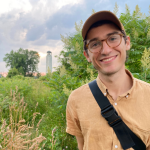 Cody Gallagher smiles in front of the Belle Isle Lighthouse