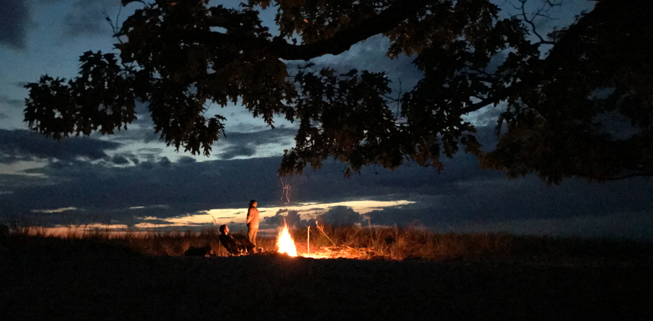 People gather at a fire along the dunes at night in Michigan