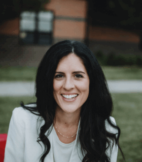 Jaime Churches smiles for the camera on a red bench