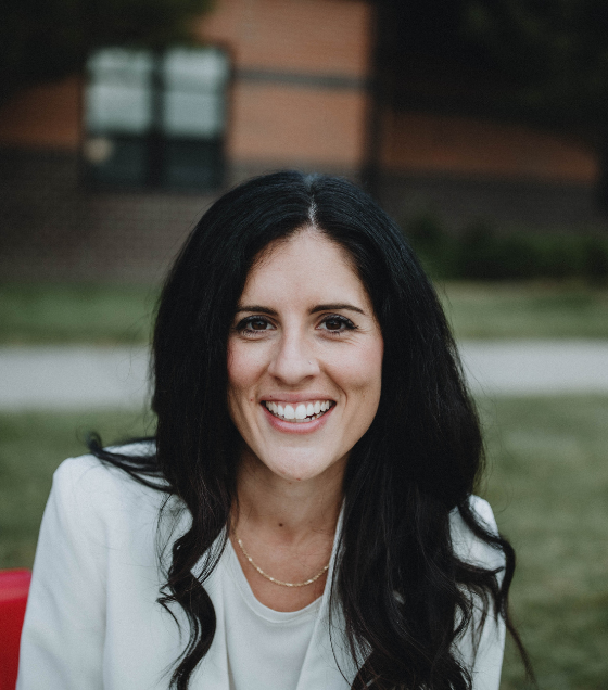 Jaime Churches smiles for the camera on a red bench