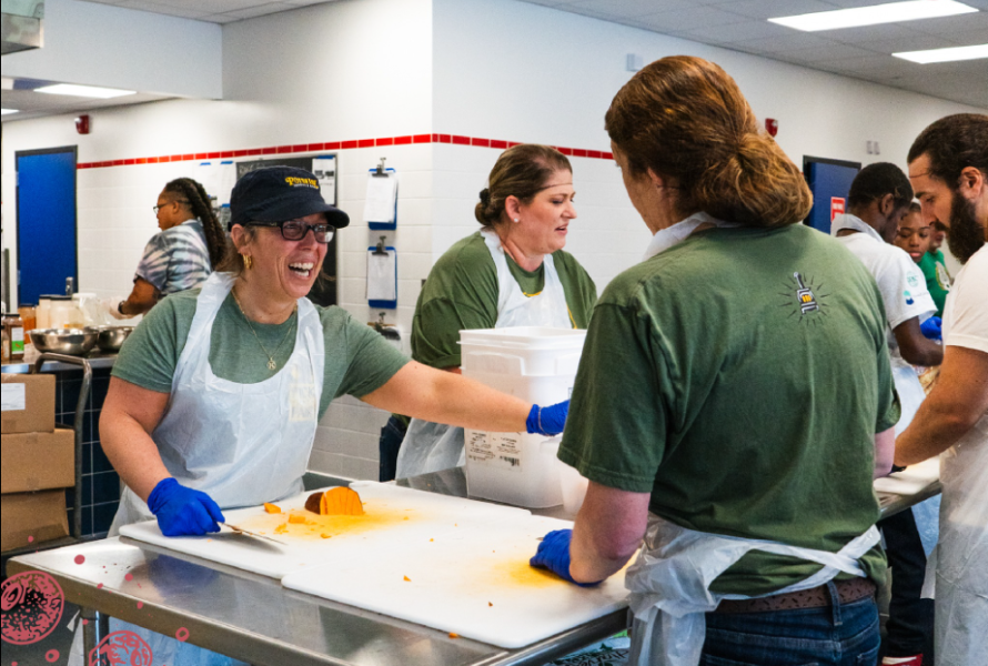 Volunteers cut up veggies in a commercial kitchen. (Photo courtesy of Make Food Not Waste)