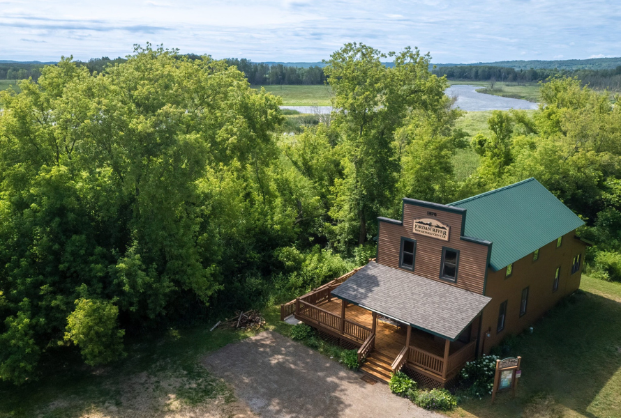 A home-like watershed center with wooden walls and porch sits just yards away from the Jordan River. (Photo courtesy of Friends of the Jordan River Watershed)