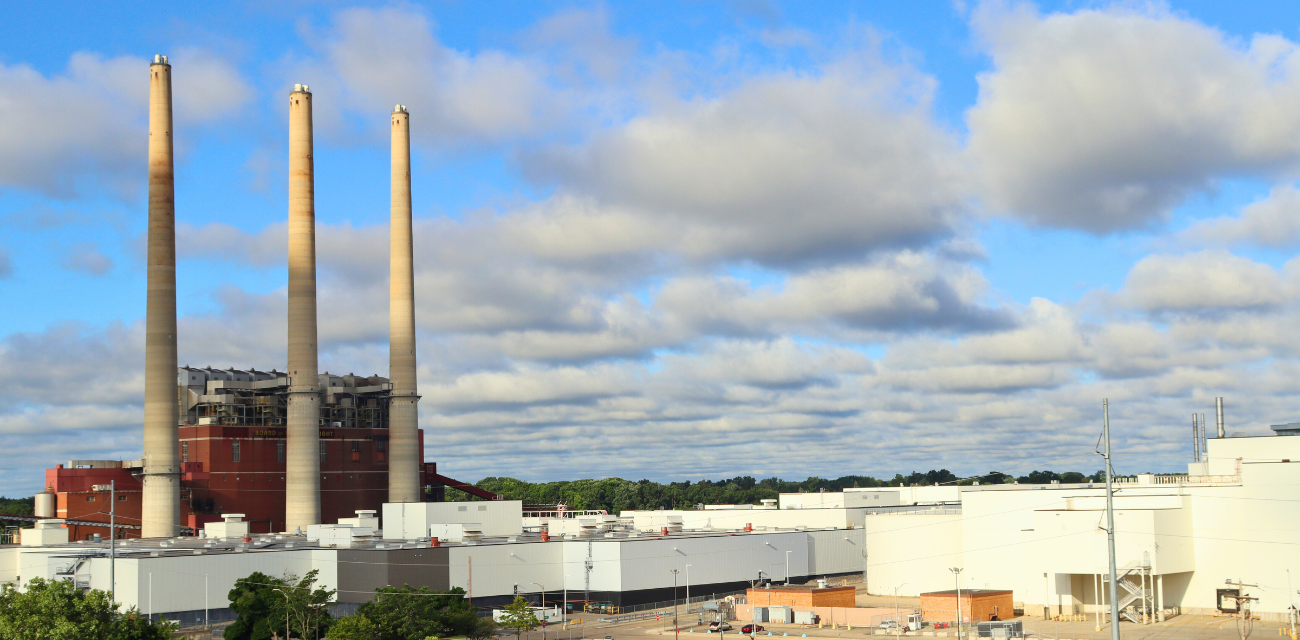 Lansing's defunct coal plant towers over a vehicle plant and trees in the heart of the city