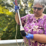 Pam Taylor shows a water sample from a Lenawee County stream (Photo courtesy of Midstory)