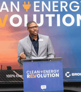 Marshall Kilgore speaks at the podium of a Clean Energy Revolution gathering.