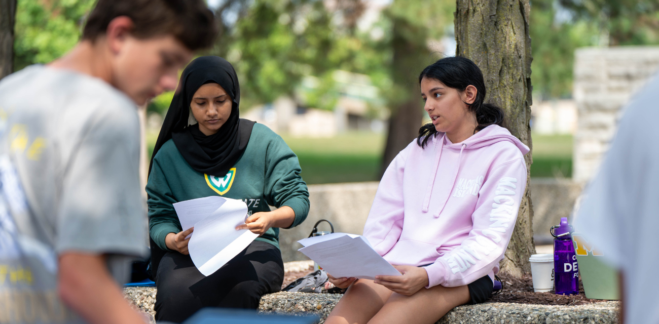 Aysha Uddin, center, and Anya Desai, right, work on articles for The Detroit Writing Room's student journalism camp. (Photo by Ella Miller for The Detroit Writing Room.)