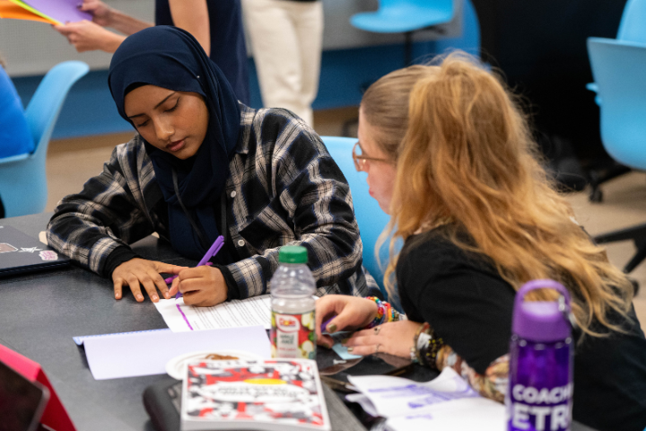 Aysha Uddin, right, and Willow Lagrou work on articles during The Detroit Writing Room's student journalism camp. (Photo by Ella Miller for The Detroit Writing Room.)